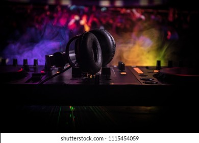 In selective focus of Pro dj controller.The DJ console deejay mixing desk at music party in nightclub with colored disco lights. Close up view