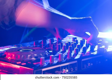 In selective focus of Pro dj controller.The DJ console cd mp4 deejay mixing desk Ibiza house music party in nightclub with colored disco lights.