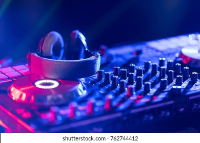 In Selective Focus Of Pro Dj Controller.The DJ Console Cd Mp4 Deejay Mixing Desk Ibiza House Music Party In Nightclub With Colored Disco Lights.