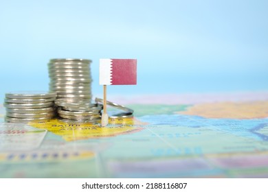 Selective focus of Qatar flag in blurry world map with coins. Qatar economy and wealth concept.	