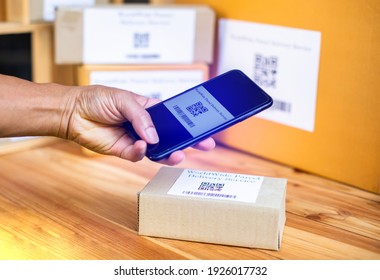 Selective focus to QR code of parcel delivery tag on smartphone to scan tag on parcel box in post office. Scan QR code and Barcode tag for receiving or sending products in industrial systems. - Shutterstock ID 1926017732