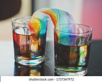 Selective focus of rainbow growing experiment at home by using tissue paper, water, glasses and color