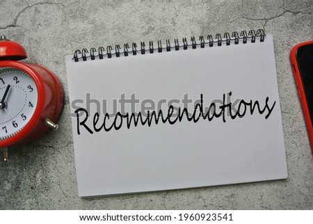 Selective focus of red clock, smart phone and notebook written with RECOMMENDATION.  Business, financial, give opinion and suggestion concept.