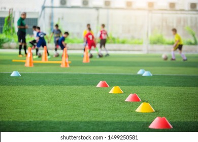 selective focus to red and yellow marker cones are soccer training equipment on green artificial turf with blurry kid players training background. material for training class of football academy. - Powered by Shutterstock