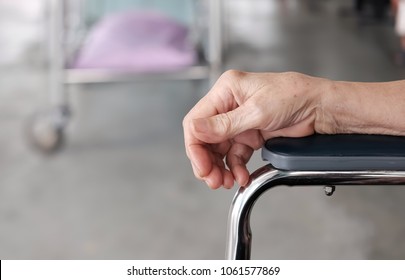 selective focus at right hand of the elderly. The old man put the arm on armrest and background with blur hospital bed. / concept of elderly , health care and medical