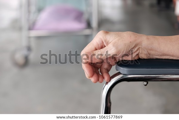 selective focus at right hand\
of the elderly. The old man put the arm on armrest and background\
with blur hospital bed. / concept of elderly , health care and\
medical
