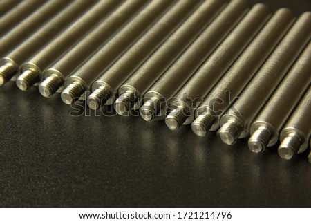 Selective focus. Rod, axis with thread on the table. Parts in a row at the factory.