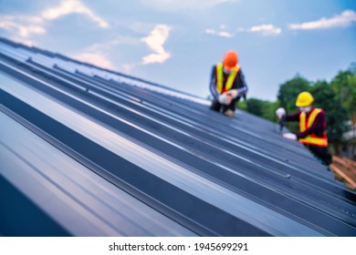 Selective Focus Roof, Roof Concept Of Residential Building Under Construction, Roofer Worker Safety Wear Using Air Or Pneumatic Nail Gun And Installing On New Roof Metal Sheet.