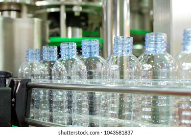 Selective focus a row of clear plastic bottles on the conveyor belt of industrial machinery, industry 4.0