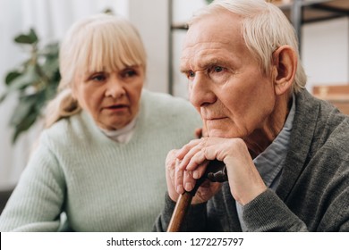 Selective Focus Of Sad Pensioner Sitting Near Senior Wife At Home 