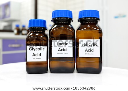 Selective focus of salicylic, lactic and glycolic acid liquid solution in dark brown glass bottle in a white chemistry laboratory background. Chemical peel for skincare research cosmetics industry.