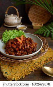 Selective Focus Of Sambal Goreng Ati Or Spicy Cooked Beef Liver In A Plate Topped With Chilli Slice, On A Wooden Table 