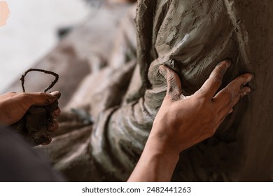 Selective focus sculptor hand molding clay.Professional artist worker creating a statue sculpture with wet clay.Handicraft production. - Powered by Shutterstock