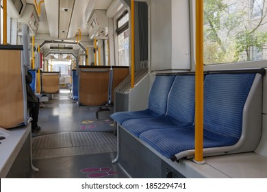 Selective focus at seat and interior view of a corridor inside passenger trains or light rail tram with blue fabric seats of German railway train system. Empty vacant passenger car inside the train.