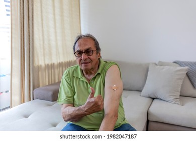 Selective Focus Of A Senior Man That Has Received His First Dose Of COVID-19 Vaccine. Man Is Pulling Up His Sleeve To Show Bandage From Vaccination. Man Pointing His Shoulder After Getting Vaccinated.