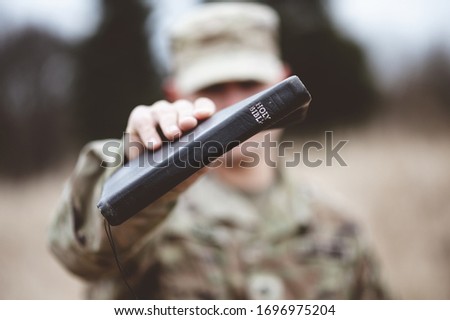A selective focus shot of an American soldier holding the Holy Bible close to the camera