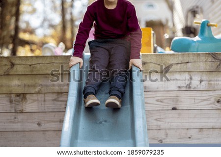 A selective focus shot of a boy sliding down a slide