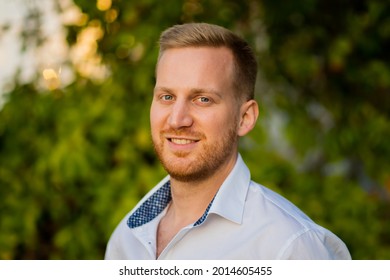 A Selective Focus Shot Of A Caucasian Male Outdoors With Green Trees And Sunlight In The Background