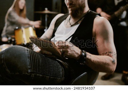 Selective focus shot of creative rock musician holding notepad working on lyrics for new song