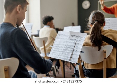 Selective focus shot of group of teenagers playing instrumental music in school orchestra at class - Powered by Shutterstock