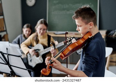 Selective focus shot of modern middle school band practicing music in classroom, copy space - Powered by Shutterstock