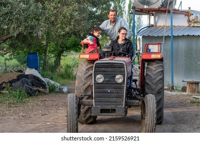 Selective Focus Shot Of Mom Driving Tractor And Grandpa And Little Girl Walking Around On Tractor.