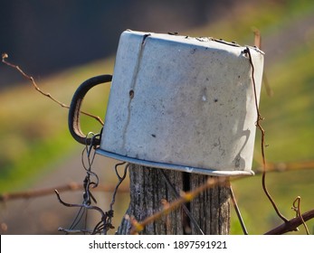 A Selective Focus Shot Of An Old Mug Among Barbed Wires