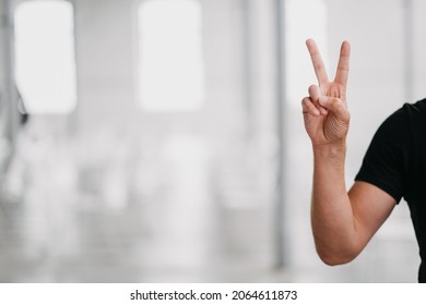 A Selective Focus Shot Of A Person Holding Up Two Fingers In A Peace Sign