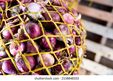 A Selective Focus Shot Of Red Onions In A Net Bag