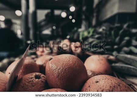 A selective focus shot of a shiny orange fruit on a sheld at a sunpermarket with blurred background