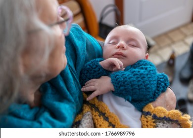 Selective focus shot of small boy sleeping in the arms of his grandmother. Out of focus upper left hand corner the proud senior gazes at the child - Powered by Shutterstock