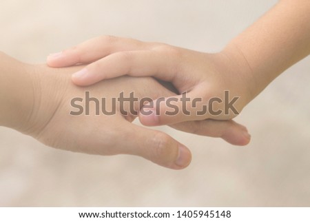 A selective focus shot of two hands of different persons touching each other giving sense of togetherness.