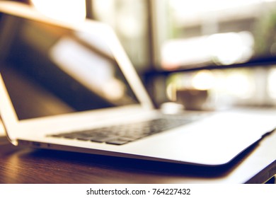 Selective focus of Side view laptop is on the work table in a conner office with morning light.