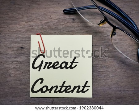 Selective focus side view text Great Content on sticky note with eye glasses on wooden background.