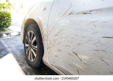 Selective Focus Side View Of White Car With Dirty Car Mud Stain. Car Dirty Headlight, Wheel, Bumper And Door Of The Car With Swamp Splashes On A Side Panel.