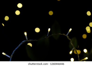 In selective focus of a small light bulbs glowing in the dark night for a new year outdoor decoration places 