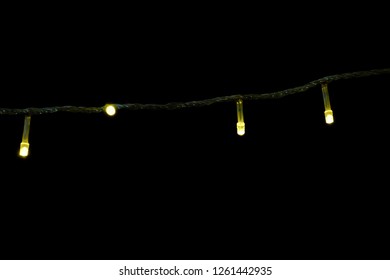 In selective focus small light bulbs on a wire and glowing in the dark night with black background 