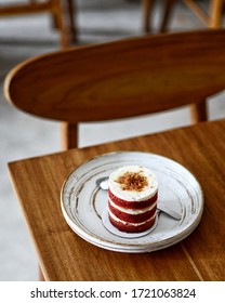 Selective Focus Of Small Red Velvet Cake On White Plate Above Wooden Table