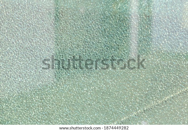 Selective focus of smashed on window\
glass with blurred backdrop, Detail of broken or cracked security\
glass of bus station, Abstract pattern texture\
background.