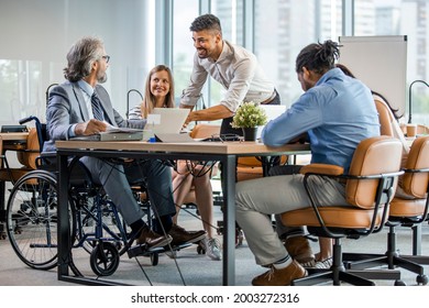 Selective focus of smiling disabled businessman and colleagues in office. Side View Of A Disabled Businessman. Young businessman greeting handicapped business partner and team. Coworker on wheelchair - Powered by Shutterstock
