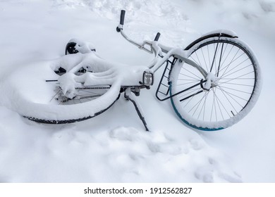 Selective focus of snow covered bicycle fall on the ground, Heavy and snowy day in winter with white fluffy snowflakes, Cycling is a common mode of transport in Holland, Amsterdam, Netherlands.