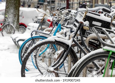 Selective focus of snow covered bicycle parked on the parking rack, Heavy and snowy day in winter with white fluffy snowflakes, Cycling is a common mode of transport in Holland, Amsterdam, Netherlands