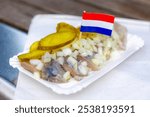 Selective focus of Soused herring (Hollandse Nieuwe) served with diced onions and sliced pickled on the side, Typical Dutch delicacy and popular street food in summer, Preserving food in Netherlands.