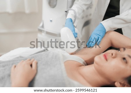 Selective focus, A specialist using laser hair removal machine in procedure laser hair removal on underarm. A woman receiving underarm laser hair removal at a modern aesthetic clinic.