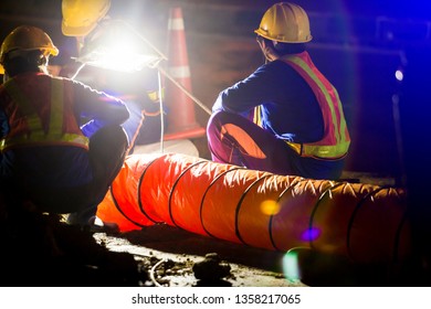 Selective Focus To Spotlight And Construction Worker Is Working At Night In Construction Site With Ventilation Pipe For Working In The Underground Tunnel, The Concept Of Hard Work And Over Time.