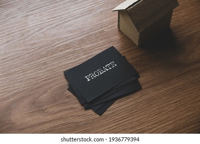 Selective Focus Of A Stack Of Black Paper Written With Probate And Small Cardboard House.