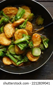 Selective Focus Of Stir Fry Broccoli And Tofu In A Spoon Against Wooden Background