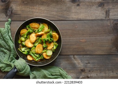 Selective Focus Of Stir Fry Broccoli And Tofu In A Pan Against Wooden Background