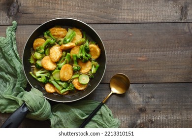 Selective Focus Of Stir Fry Broccoli And Tofu In A Pan Against Wooden Background