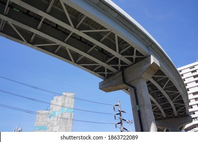 Selective focus, structure under ceiling sky train concrete bridge in Bangkok. Pillar support underneath. Buildings, power pole with cables and blue sky background. Concept of structure, bridge.